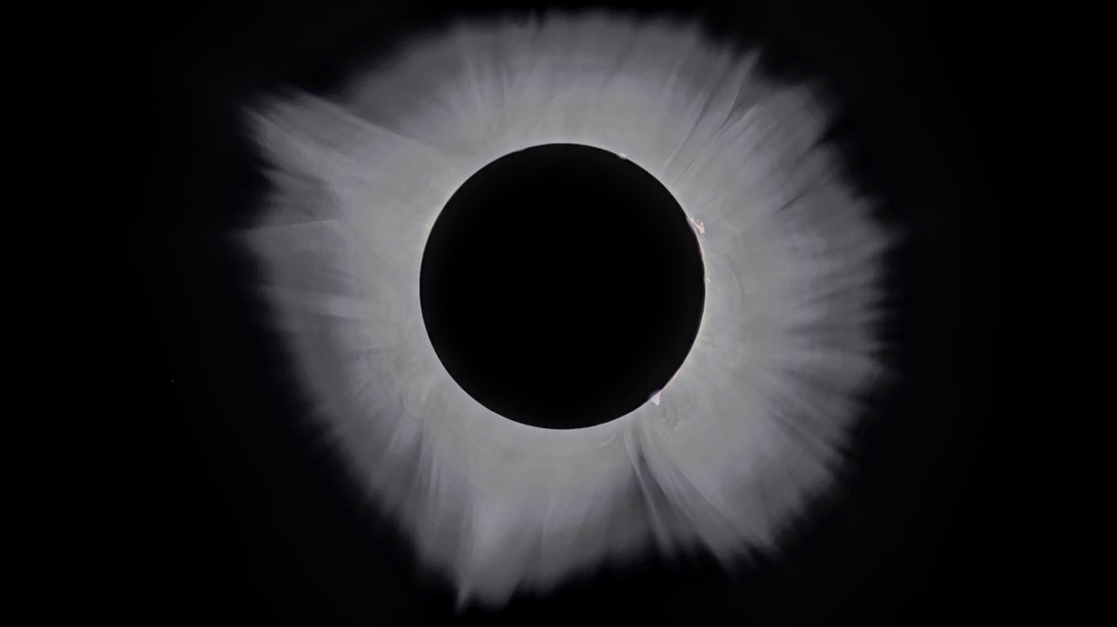 The same corona after exposure fusion: the faint outer corona and its streamers are visible far beyond the inner ring, against a neutral sky.